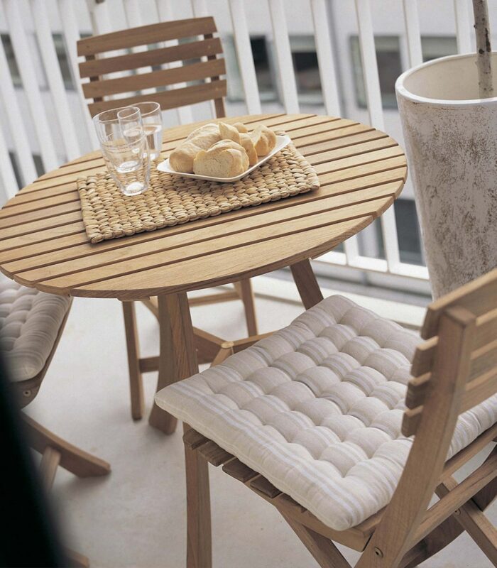 A table with two chairs and a basket of food on top.