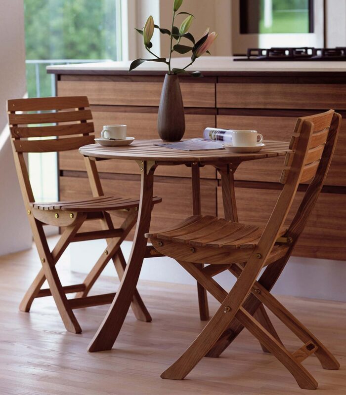 A table with two chairs and a vase of flowers.