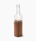 A candle in a glass bottle with wood base.