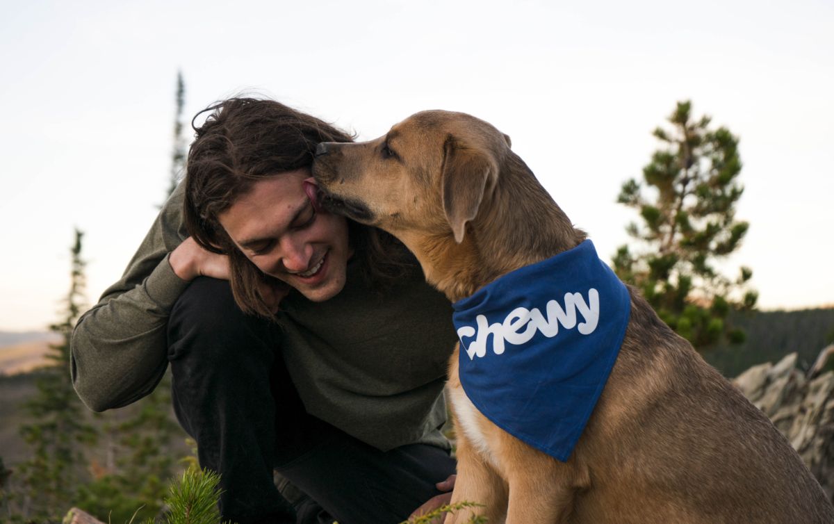 A man and his dog are kissing each other.